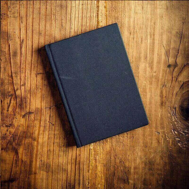 Closed navy notebook sitting on a wooden surface